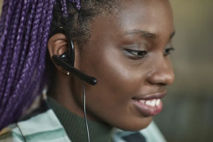 A woman wearing a headset and smiling while working in customer service.