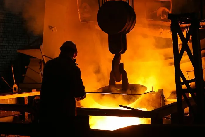 An industrial worker standing near molten metal, tied to stories of workers who got fired quickly.