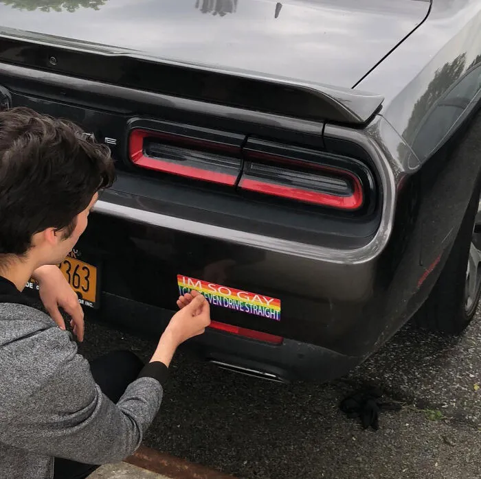 A person sticking a rainbow bumper sticker on a car bumper for a petty revenge story