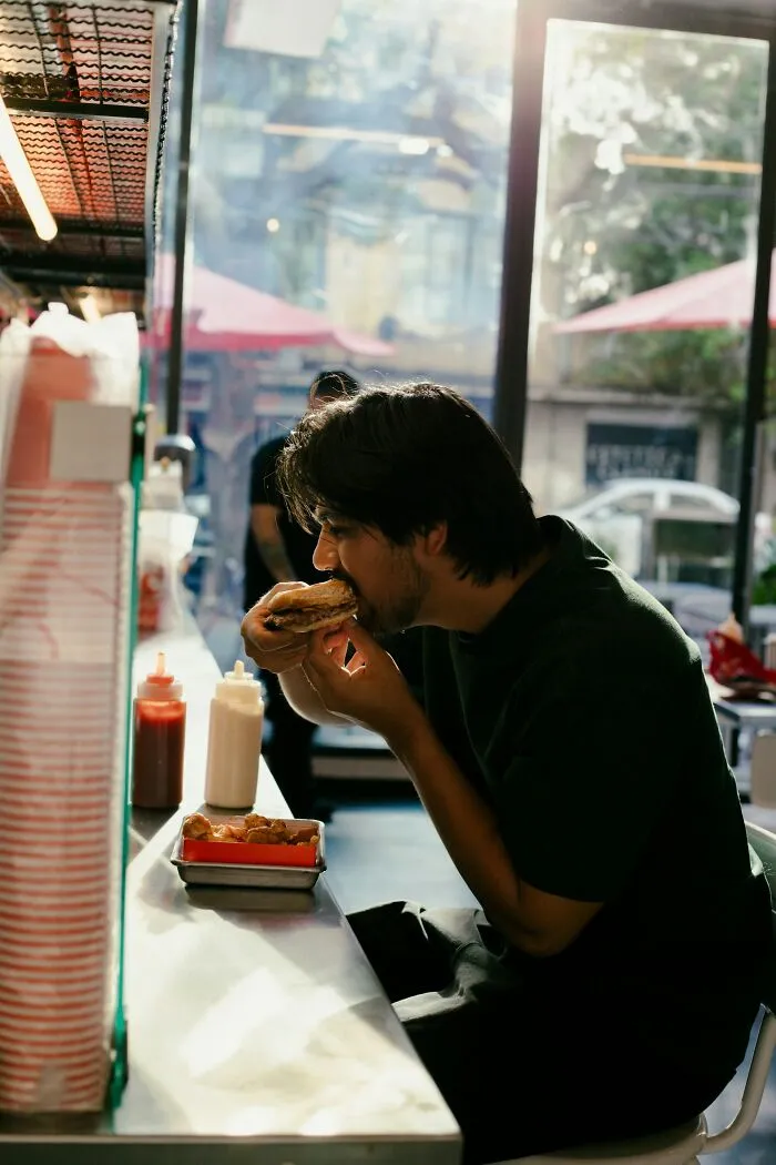 A man eating a burger, illustrating wild and infuriating stories about poor dining experiences.
