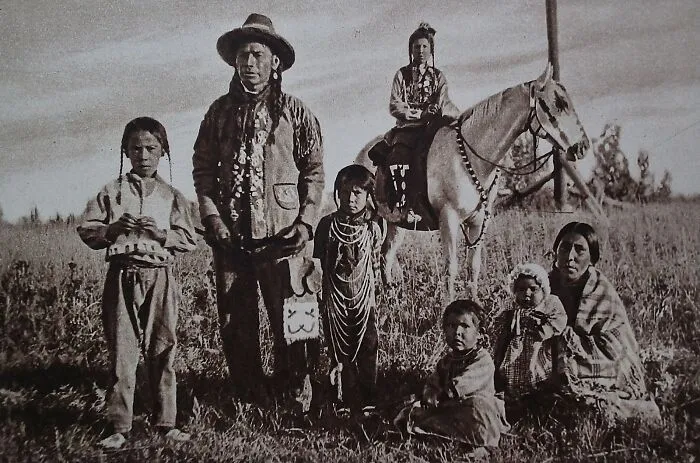 Rare historical photo of Native American family in traditional dress in a field
