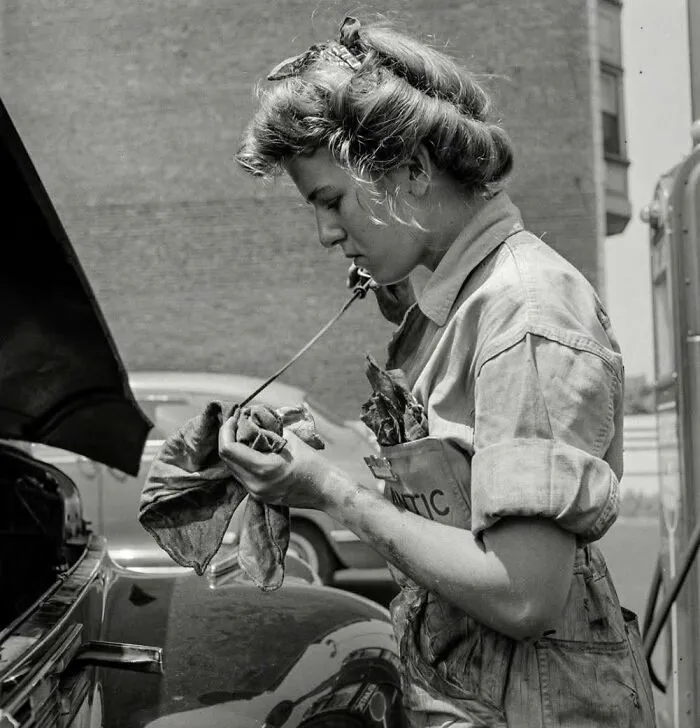 Woman mechanic working on a car engine in vintage historical photo
