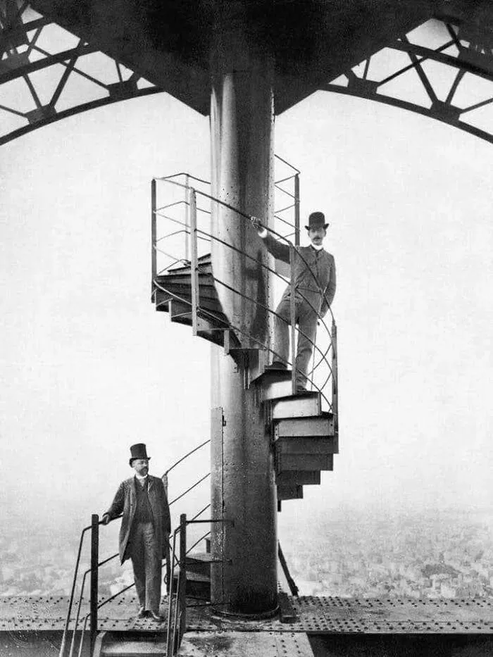Men on spiral staircase atop the Eiffel Tower in vintage photo