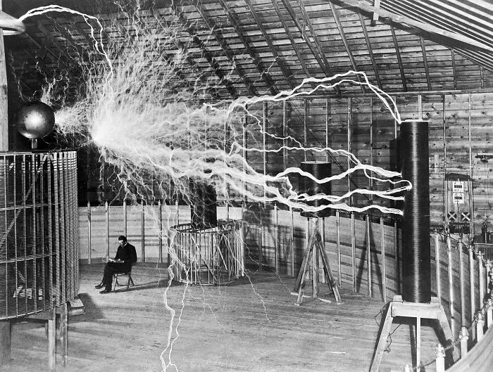 Rare historical photo of Nikola Tesla sitting near electrical arcs in lab
