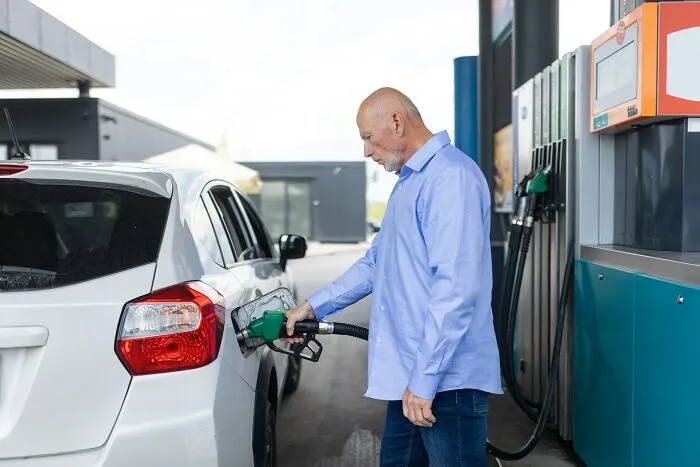 Man refueling his car at a gas station, symbolizing inadequate work bonuses given by bosses
