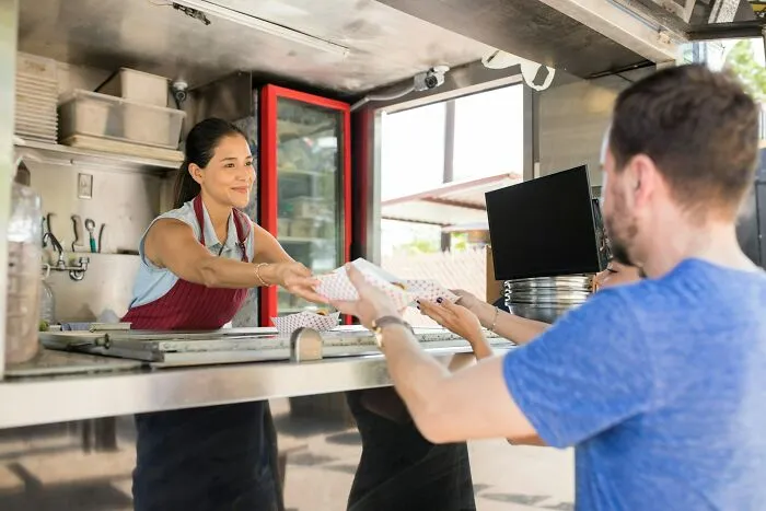 Food truck employee serving customers, illustrating cheap company bonuses from out of touch bosses