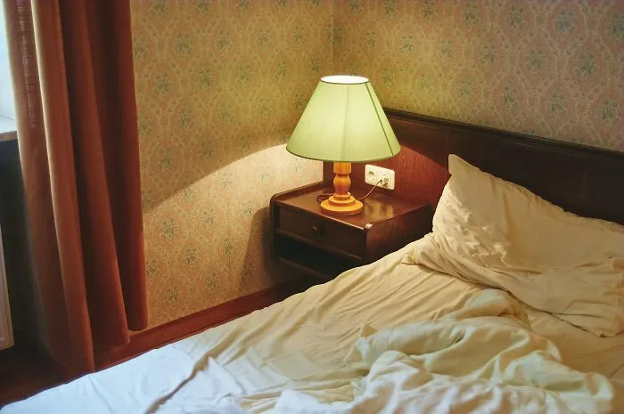 A cozy bedroom setting showcasing partners questioning intelligence while looking at an old-fashioned lamp