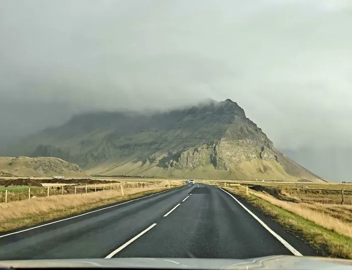 Mountain view from a highway with overcast sky and green fields