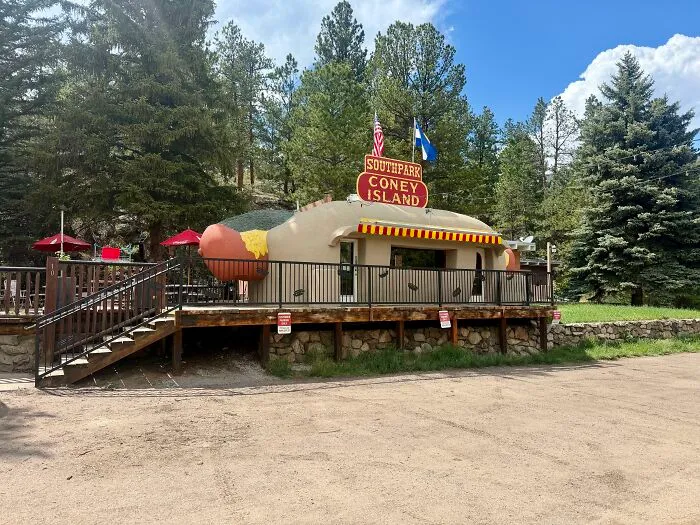 Quirky hot dog shaped building with outdoor seating in wooded area