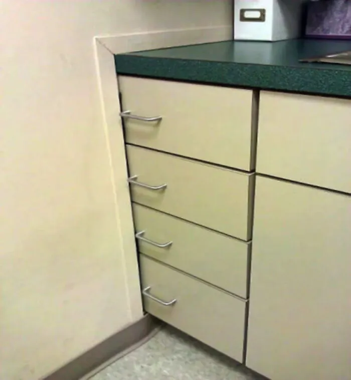 A kitchen renovation fiasco with drawers installed in a corner, unable to open due to overlapping trim.