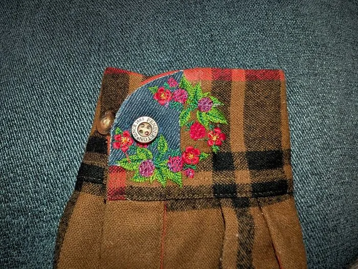 Detailed floral embroidery on a plaid cuff, showing how creativity can save money through mending.