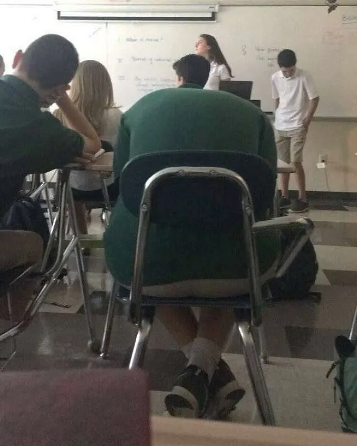 A student slouched in a classroom chair creating a perfectly confusing shape.