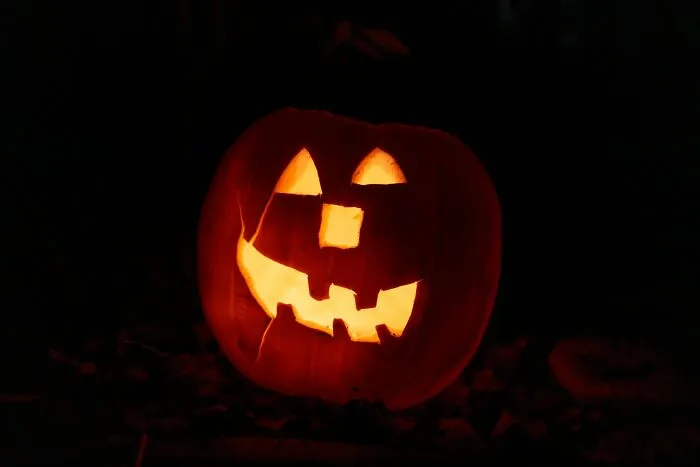 A glowing carved jack-o-lantern illuminated in the dark for scary Halloween night.