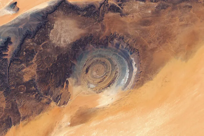 Surreal satellite photos depicting the eye-like Richat Structure formation in the desert terrain.