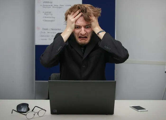 A stressed businessman looking at his laptop after a costly slip-up