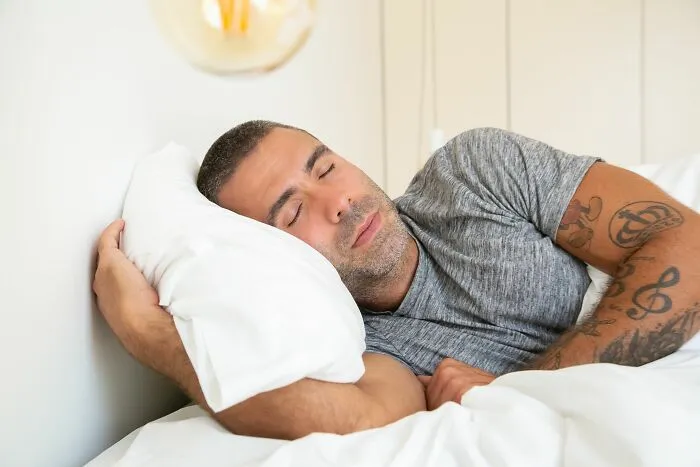 Man sleeping peacefully on white pillow in bed