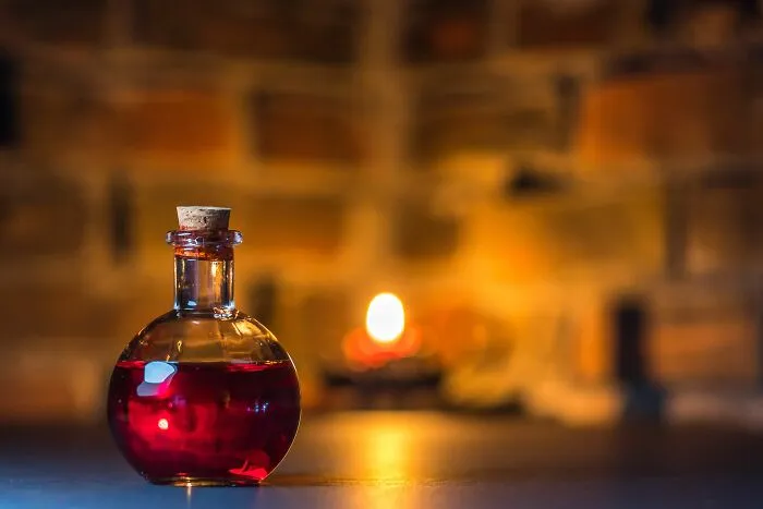 Red liquid in a small glass bottle with cork on blurred background