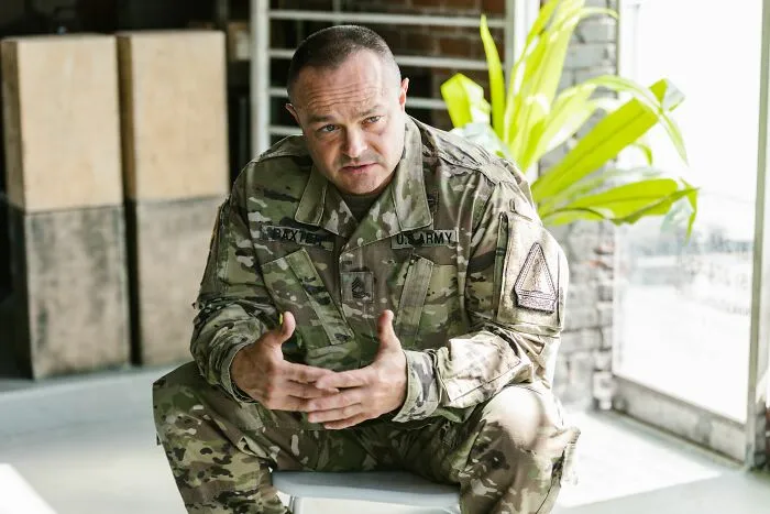 Army soldier in camouflage uniform sitting indoors
