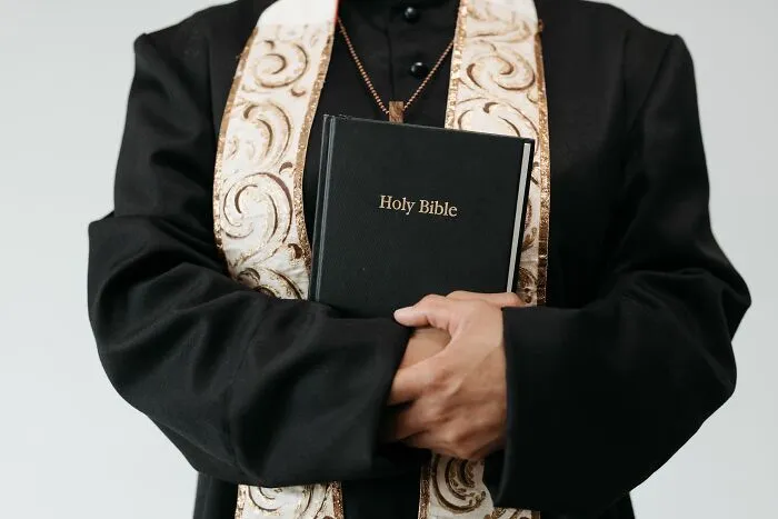 Clergyman holding Holy Bible wearing religious stole and black robe