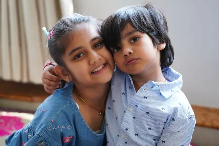 Young siblings hugging and smiling indoors closeup portrait