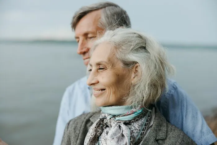 Older couple smiling by the water sharing secrets and happy moments