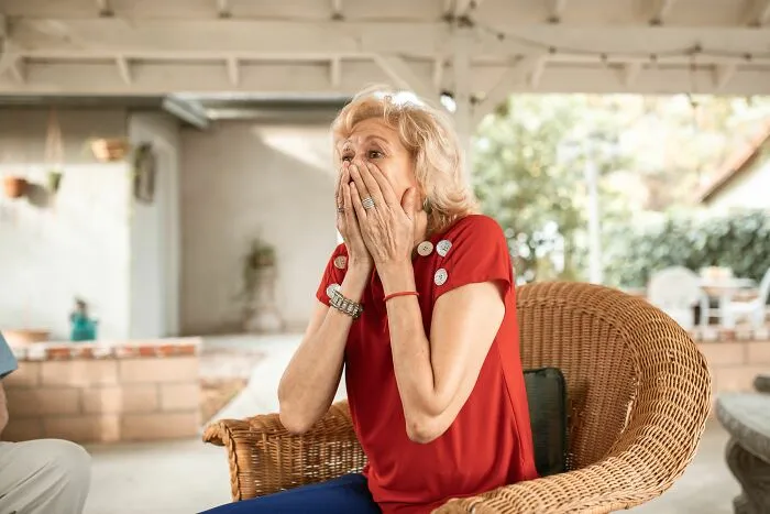 Shocked elderly woman covering mouth in surprise