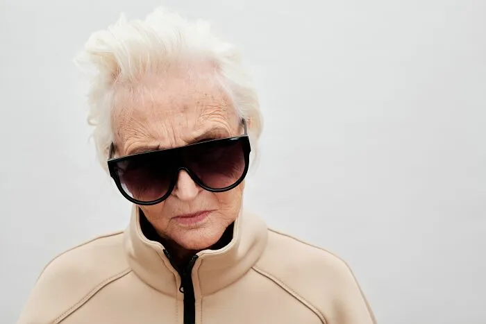 Elderly woman wearing sunglasses with a serious expression
