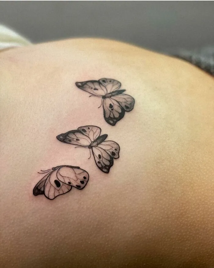 Black and white butterfly tattoo in flight on shoulder skin