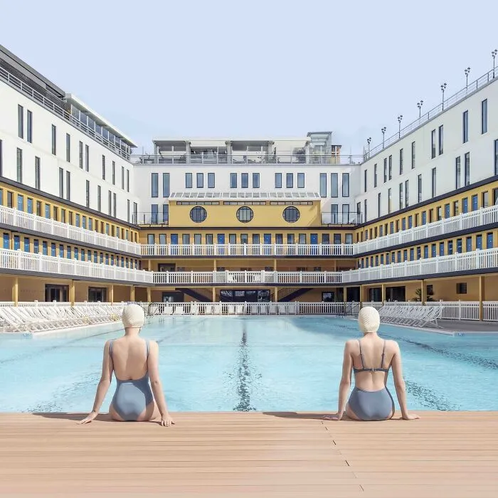 Symmetrical view of two swimmers at a pool displaying the beauty of buildings and spaces
