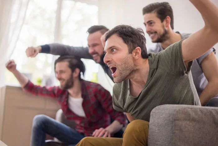 A group of guys cheering loudly on a couch, capturing the energy of living with guys