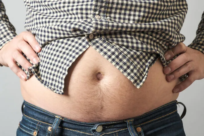 A close-up of a man showing off his belly, highlighting living with guys physical traits