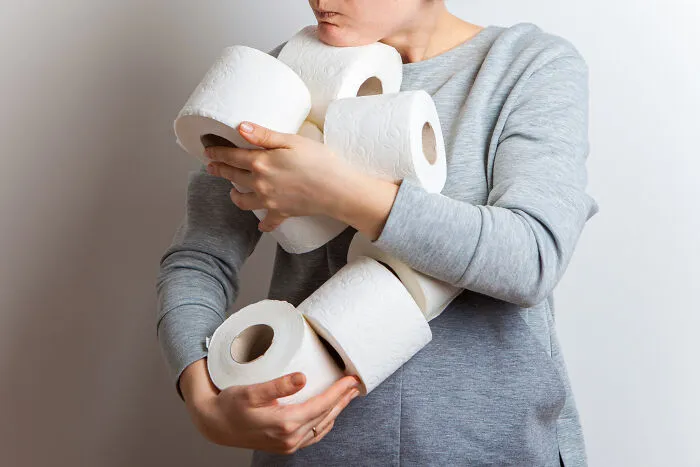 A person holding multiple toilet paper rolls, sharing experiences of living with guys.