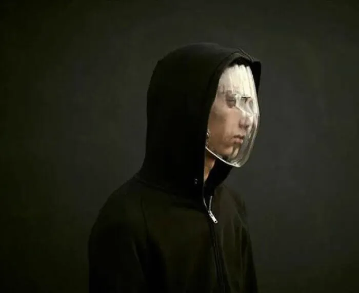 Persona con sudadera negra y capucha usando una máscara facial plástica transparente, imagen interesante y curiosa encontrada.