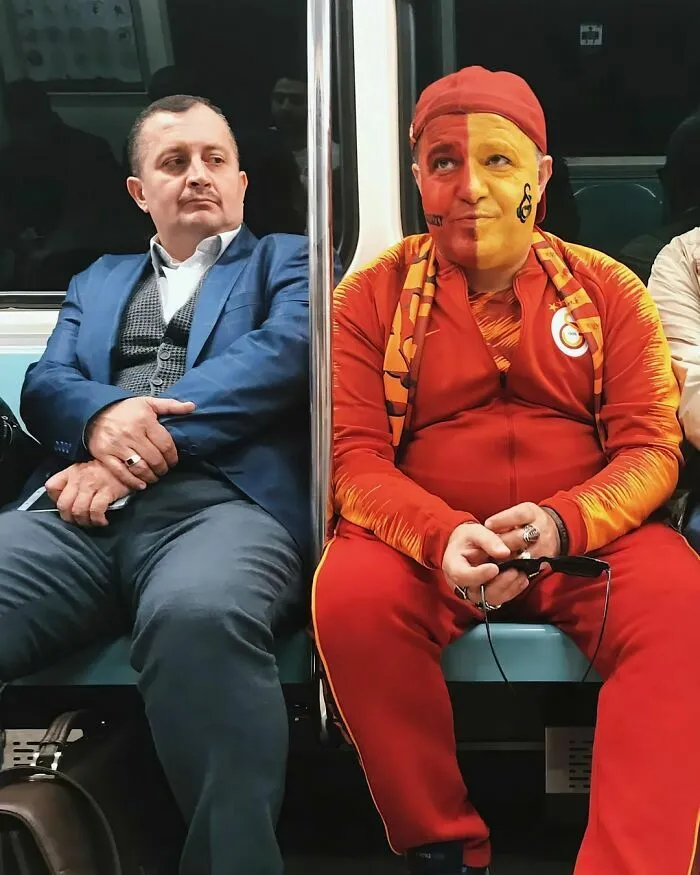 Dos hombres en el metro con atuendos opuestos, una de las mejores escenas callejeras llenas de contraste.