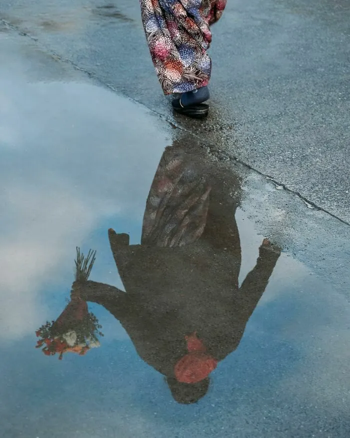 Reflejo en un charco de una persona con un ramo, muestra de fotos de escenas callejeras sorprendentes.