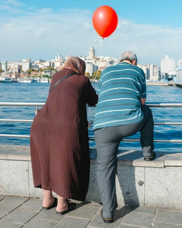 Pareja junto al agua con un globo rojo en una de esas fotos de escenas callejeras con sincronización perfecta.