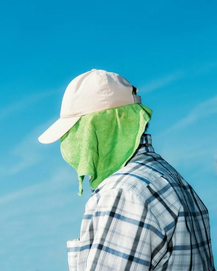 Hombre cubriendo su rostro con una toalla verde en impactantes escenas callejeras con sincronización perfecta.