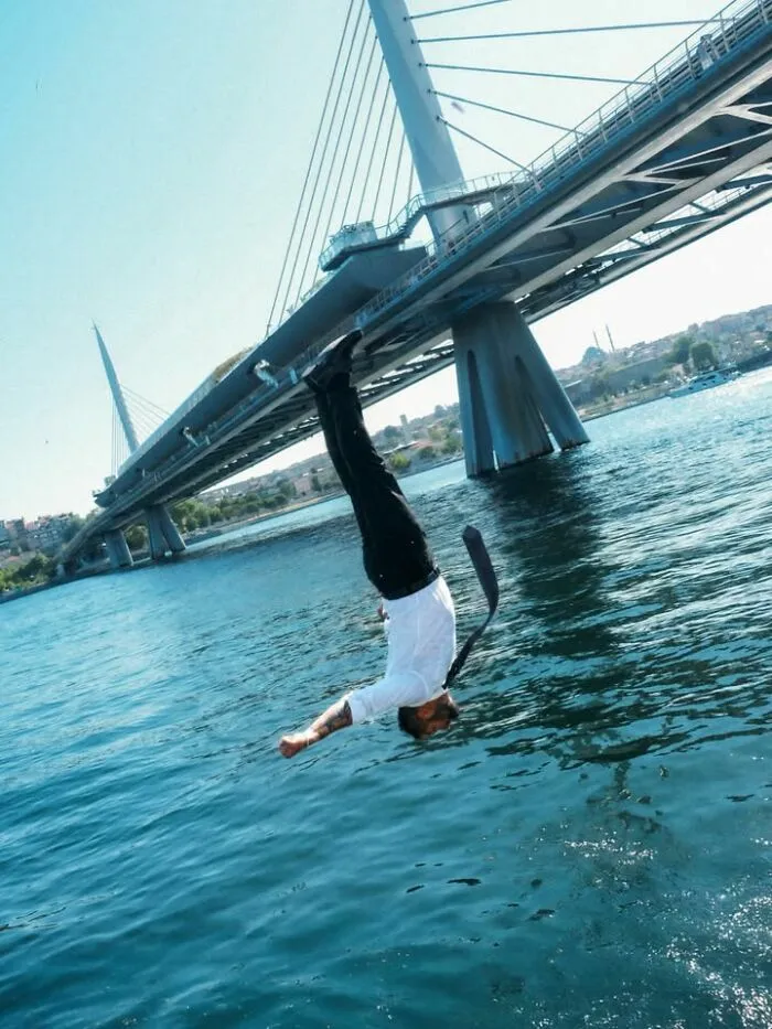 Hombre saltando al agua vestido de traje, una de las mejores escenas callejeras con sincronización perfecta.