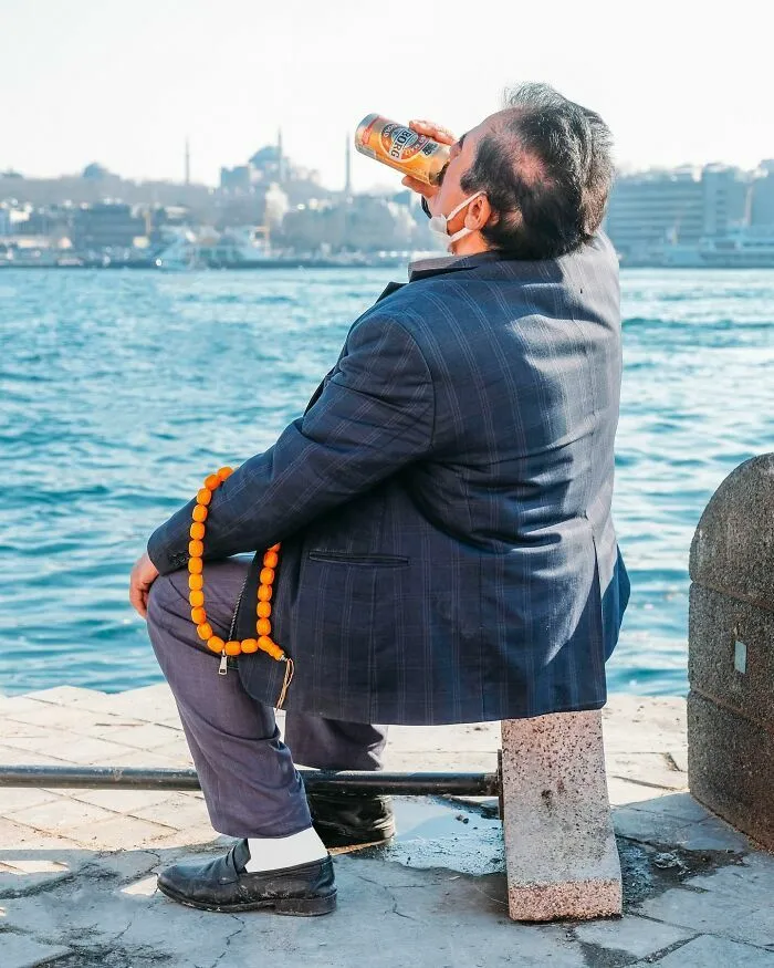Hombre bebiendo frente al mar captado en fotos de escenas callejeras con una sincronización tan perfecta.