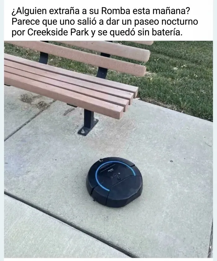 Aspiradora robot perdida junto a un banco del vecindario en un parque