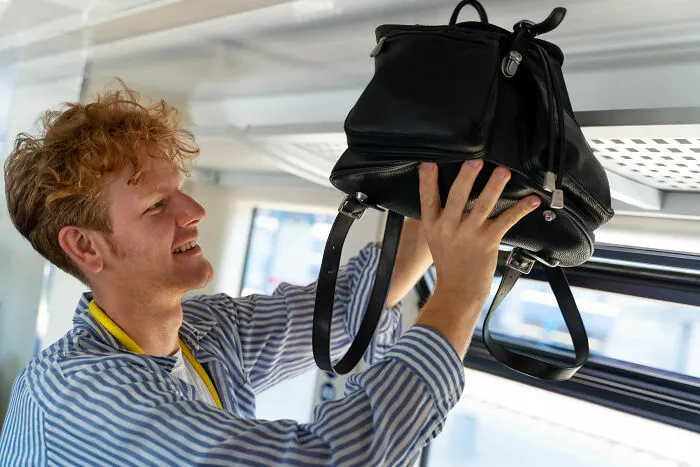 Pasajero guardando mochila en compartimento superior del avión