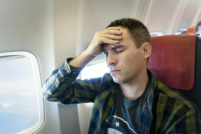 Pasajero estresado con dolor de cabeza durante vuelo