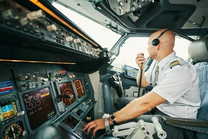 Piloto de avión en cabina comunicándose por radio