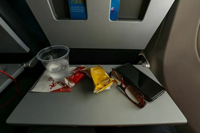 Mesa abatible con snacks y bebida en asiento de avión