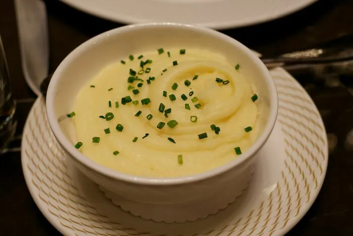Puré de papa con cebollino en plato blanco servido en avión