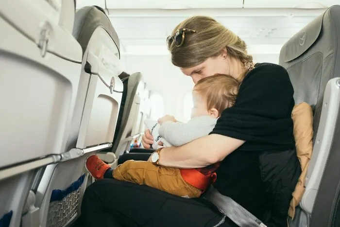 Madre con niño jugando en asiento de avión durante vuelo
