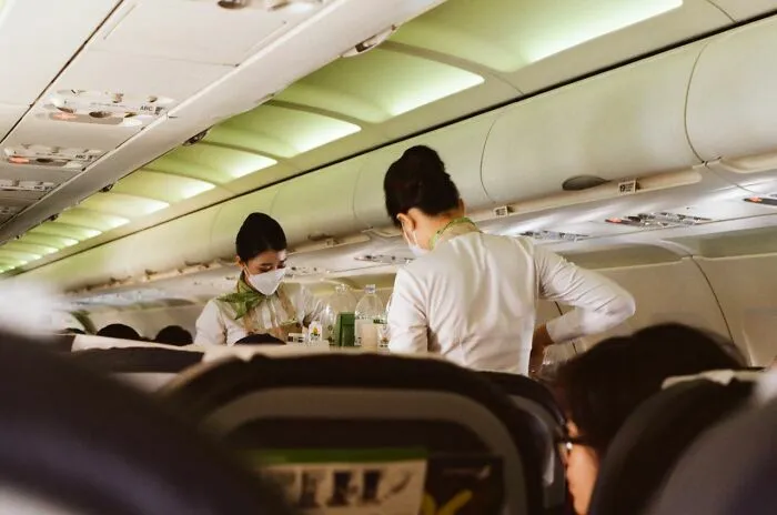Azafatas atendiendo pasajeros en avión durante servicio a bordo con pasajeros visibles