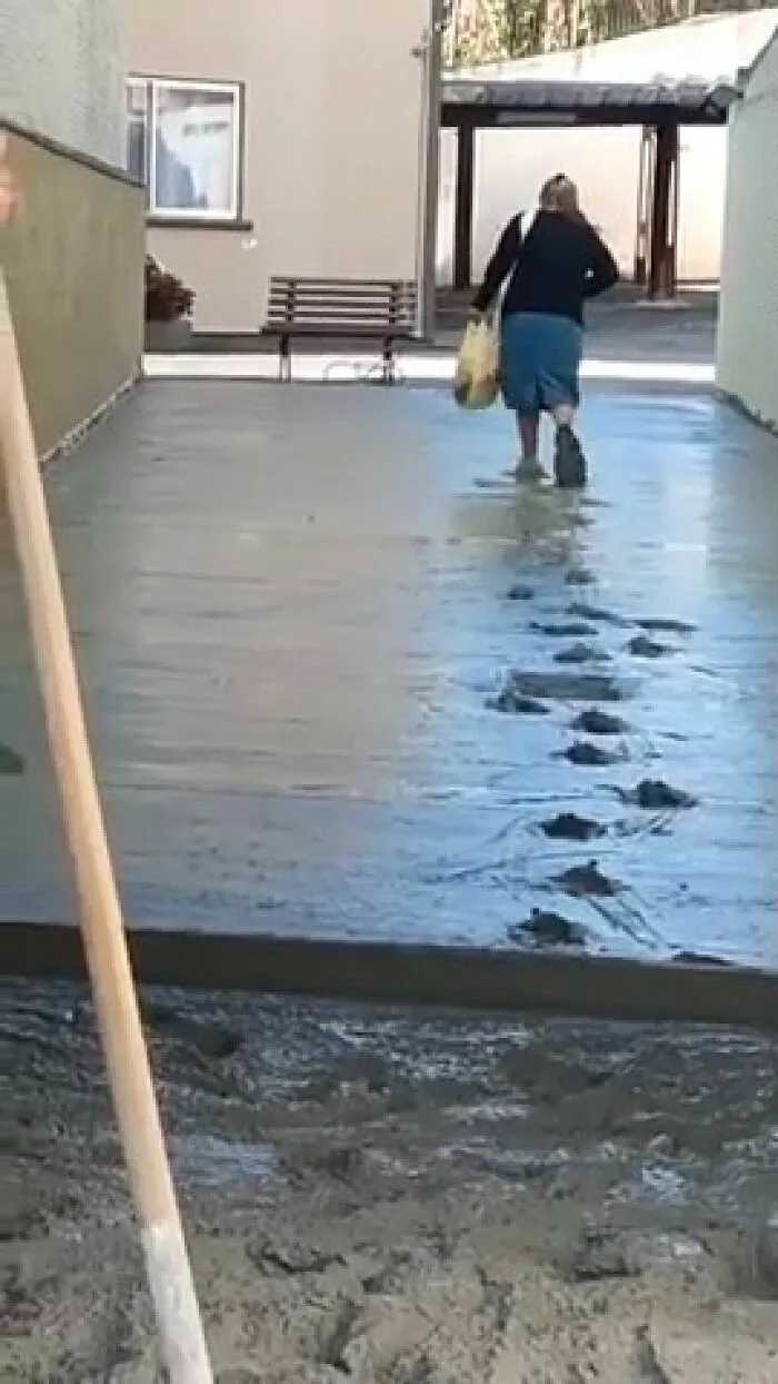 Mujer egocéntrica camina sobre cemento fresco dejando una fila de huellas marcadas