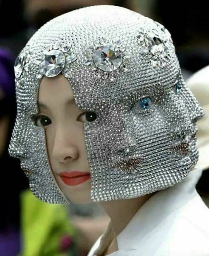 Mujer con un casco de brillantes que forma rostros tridimensionales, mostrando un increíble talento.