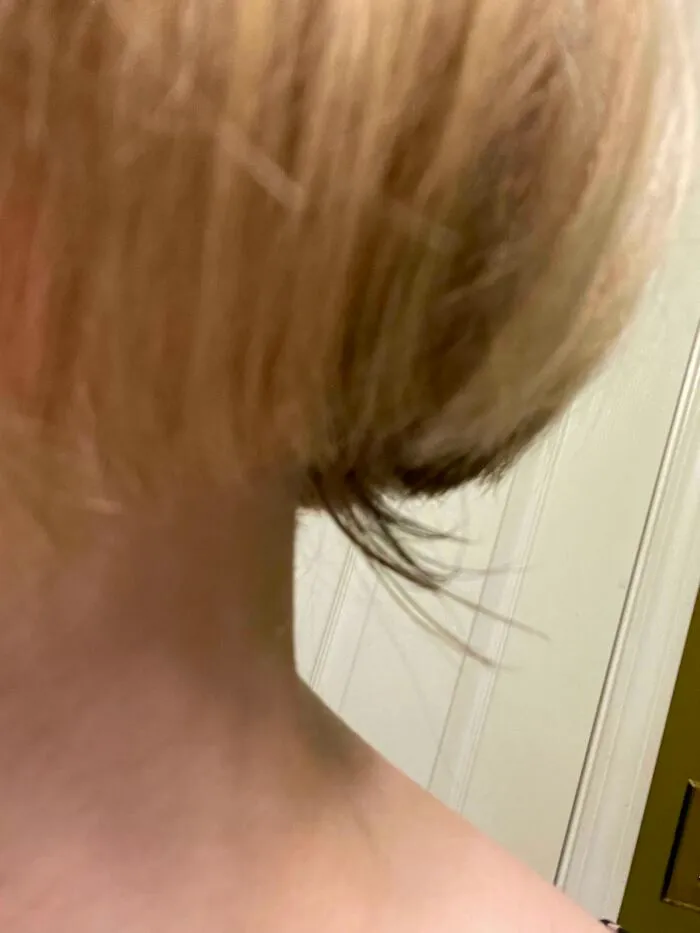 Un mal corte de pelo en un salon de belleza que muestra capas desiguales y mechones largos sin sentido.